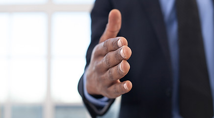 Businesses man reaching for a handshake with the viewer