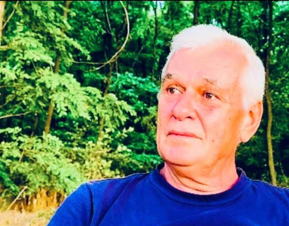 Artist Marian Nastase privind ganditor in departare, pe fundalul padurii