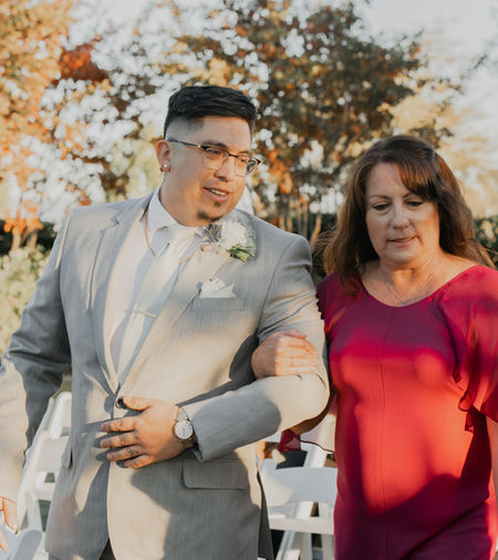 Groom walking down the aisle with his mom at a wedding