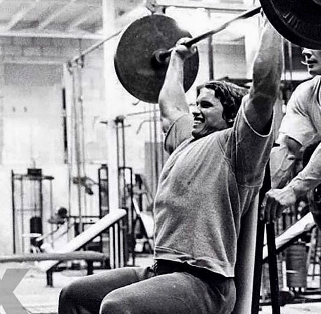 Arnold Schwarzenegger performing Overhead Press