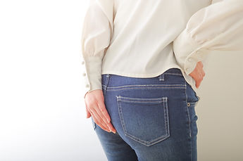 お尻を手で押さえる女性