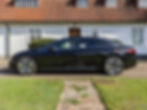 Black Mercedes EQS sedan parked infront of old white house.