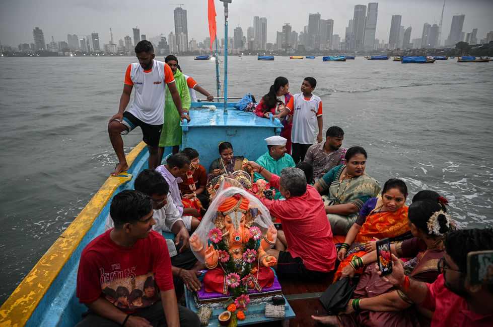 Hindu devotees ride a fishing boat as they venture into the Arabian sea in order to immerse the idols of Hindu deity Ganesh, during Ganesh Chaturthi festival, in Mumbai on 23 September 2023.