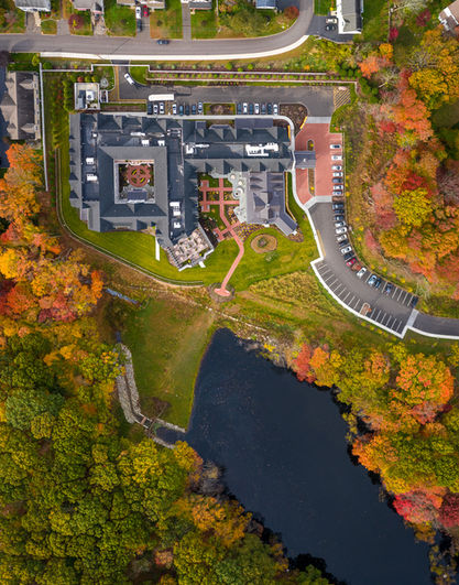 Overhead aerial drone view of Maplewood at Southport senior living campus in Southport Connecticut surrounded by fall foliage and pond