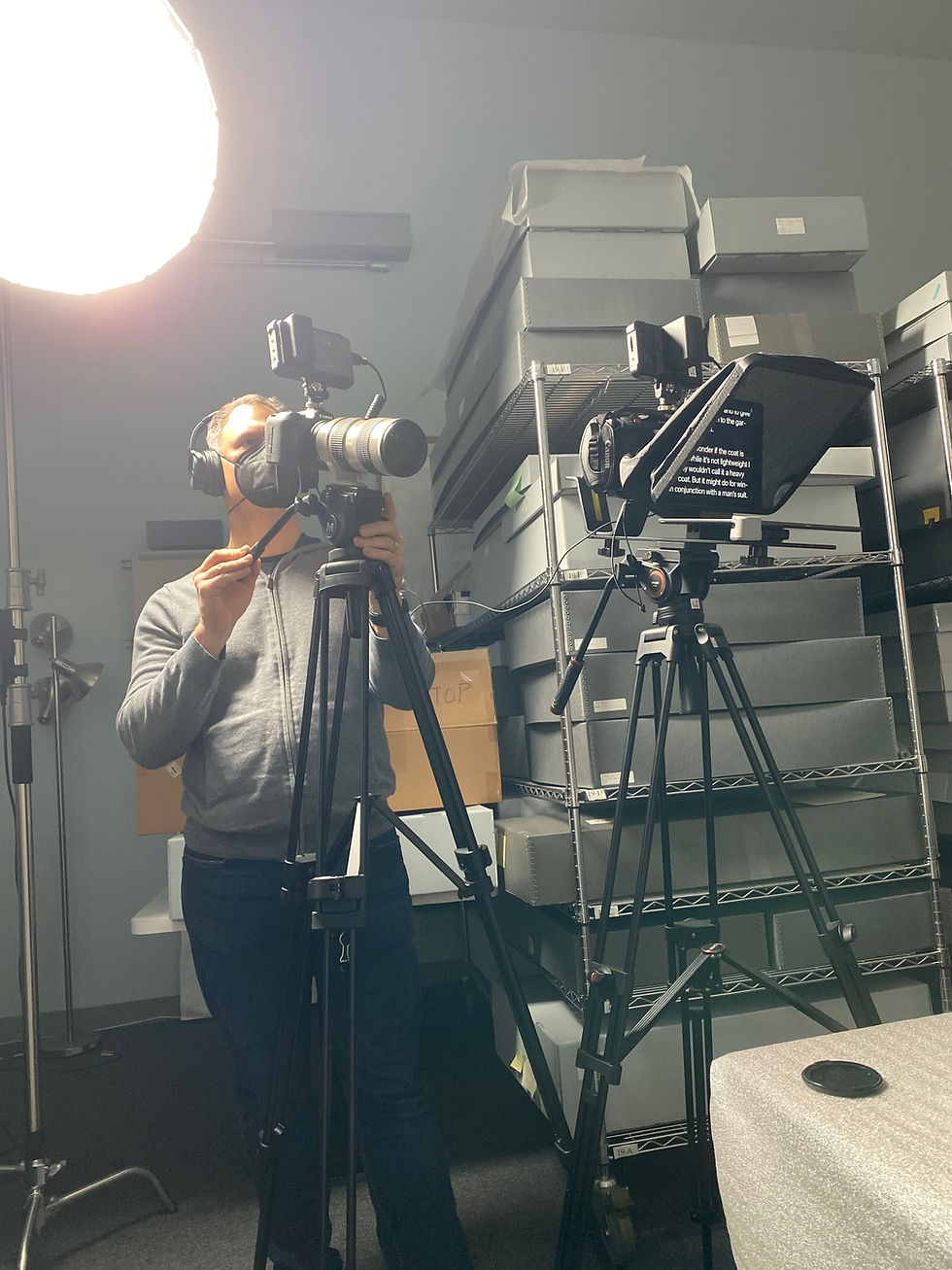 William Sarris of William Sarris Productions assisting with oral history video services documentation in an archive storage room with organized archival boxes on shelving.