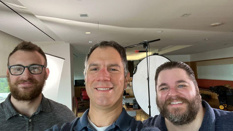 Rui Pinho with longtime collaborators Will Sarris and Luke Chase during a corporate video shoot, standing in front of lighting and production equipment.