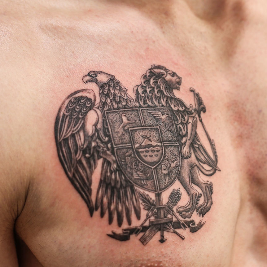a black and grey tattoo of a family crest on the chest