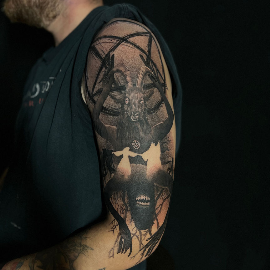 a dark realism tattoo of the demon goat the behemoth on the upper arm
