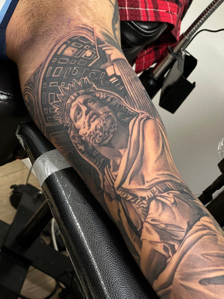 a black and grey realism tattoo of a statue on the inner arm