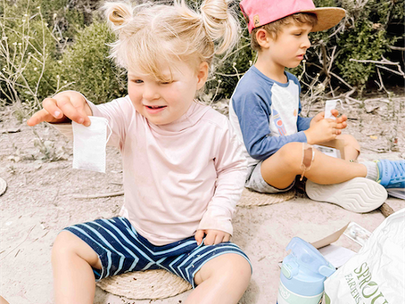Child filling a tea bag with tea leaves, building fine motor skills and sensory awareness at Oak Riparian Park in Oceanside.