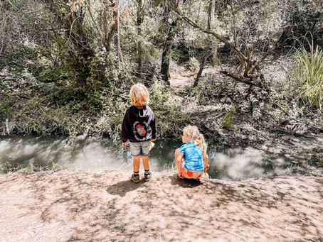 Two children looking into a creek at Buena Vista Park in Vista, exploring nature and building curiosity through Place-Based Education.