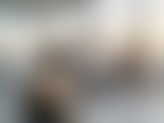 A diverse group of three expatriate professionals, a man and two women, smiling as they collaborate on a tablet in a modern office. Large windows behind them show a panoramic sunset view of the Dubai skyline, featuring the Burj Khalifa. This illustrates the professional lifestyle and high-paying job opportunities available in Dubai.