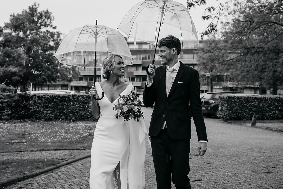 Bruidspaar met paraplu's in de regen op hun trouwdag