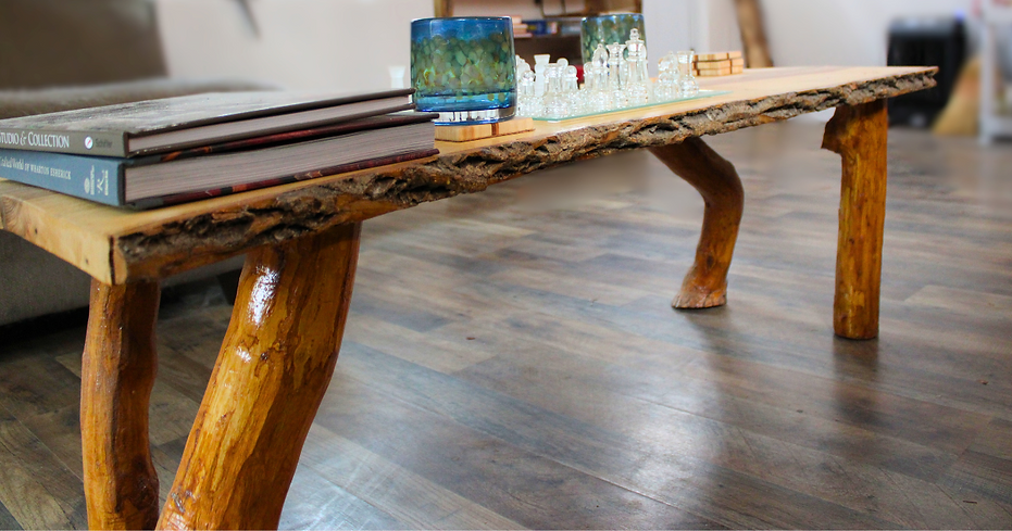 Bark inclusion shown for a live edge table. On top of the table there are books, cups, wooden coasters, and a chess set. The background is blured out to highlight the live edge table.