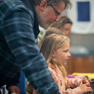 A family sitting together, each using a phone or tablet, representing children navigating technology, social media, and AI safely with parental guidance at the First Phones Family workshop.