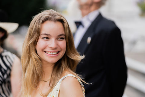 Natural, shallow depth-of-field portrait of a smiling wedding guest during a summer wedding in London.