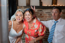 Candid photo of guests laughing and making silly faces at a wedding party.