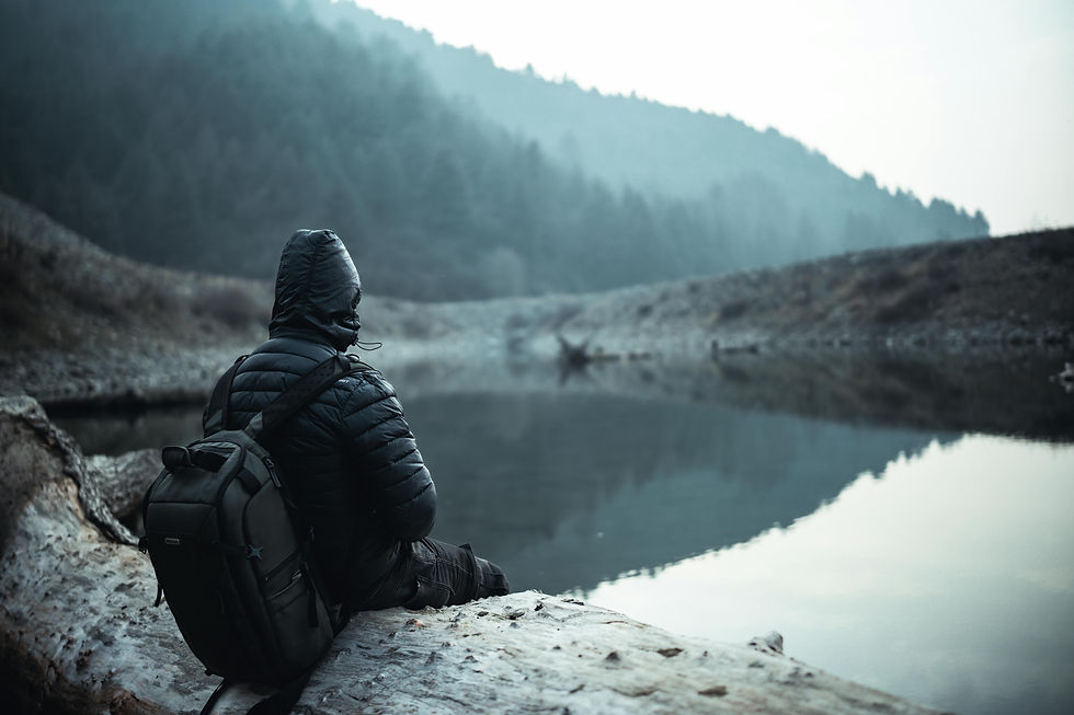 Person sitting alone by a foggy mountain lake, in quiet reflection