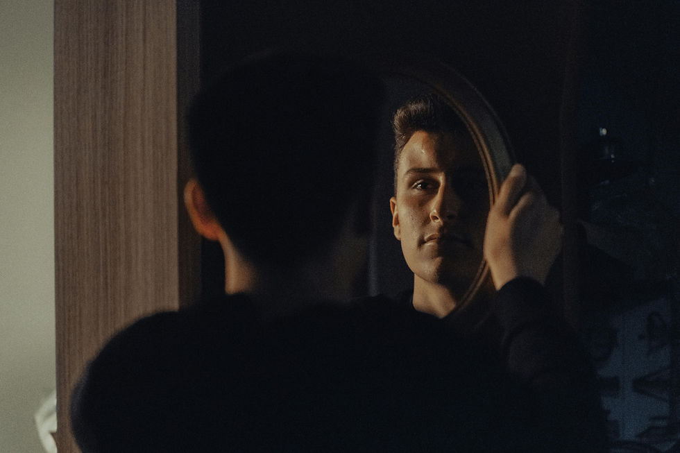 Man looking at his reflection in a dark mirror, confronting his self-image