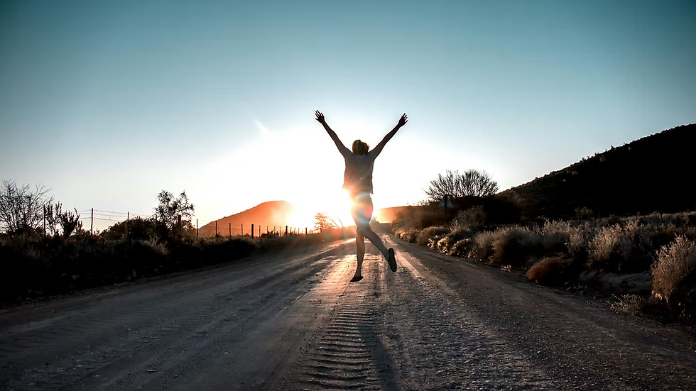 Person standing at sunrise with arms lifted, embracing healing and new beginnings