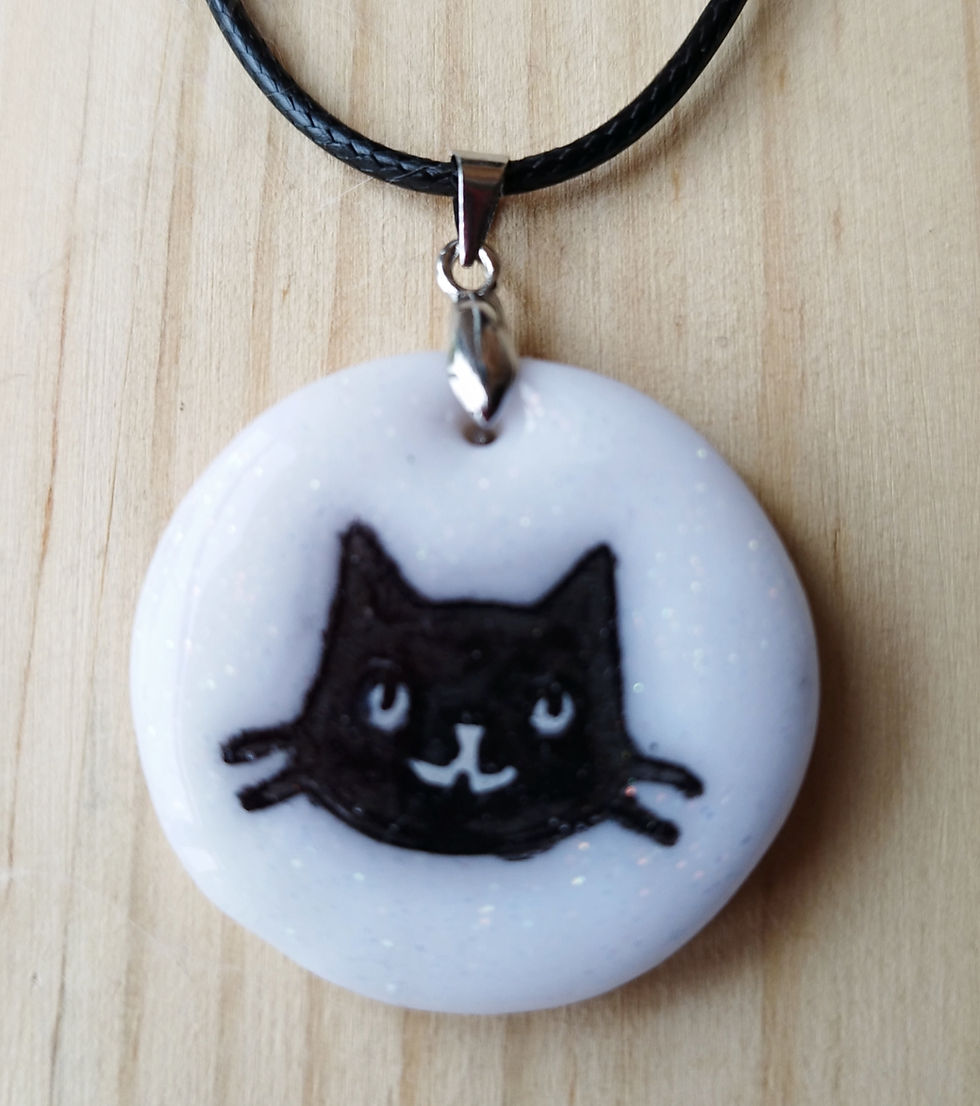 Collier pendentif rond blanc pailleté avec tête de chat noir.