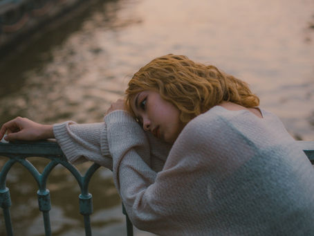 Girl resting on a gate, looking thoughtful