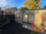 Modern garden room with sliding glass doors, brick exterior, and paved patio in Woking, Surrey.