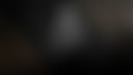 Eric Kuhlmann performing on stage at the 2025 South Australian Pride Gala, singing into a microphone while playing an acoustic guitar, standing against a dark curtain backdrop with soft lighting and gold graphic accents framing the image.