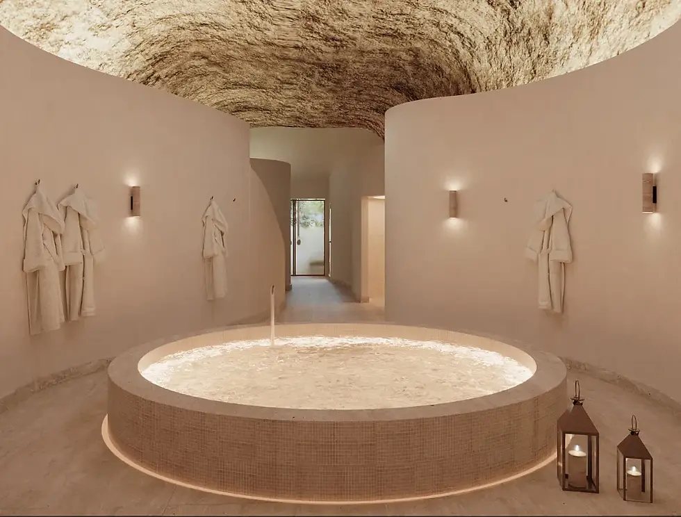 Spa elegante com piscina circular, roupões nas paredes, lanternas no chão e teto em pedra; ambiente calmo e luxuoso.
