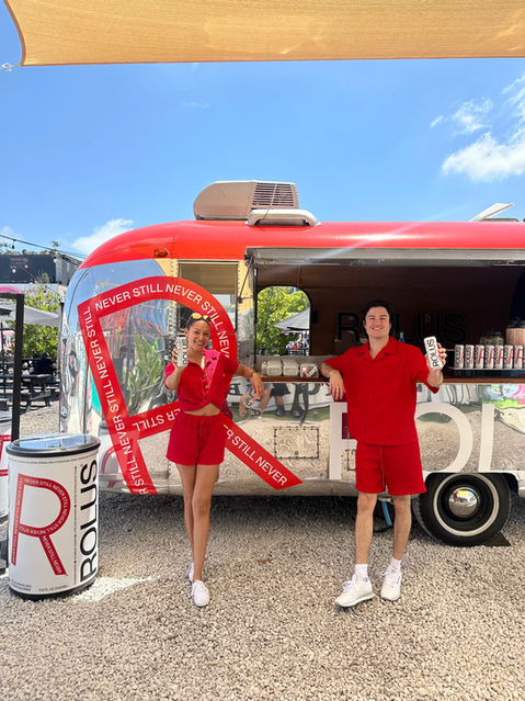 Brand ambassadors smiling and posing in front of StarBar Miami branded vintage Airstream mobile bar at a marketing event.