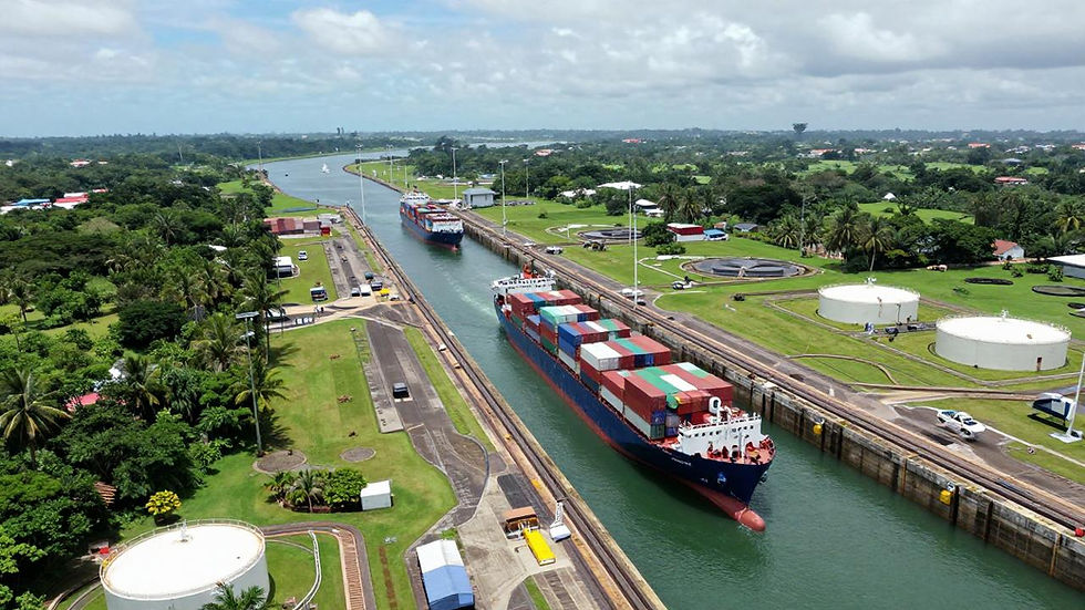 Aerial photograph of Panama Canal third set of locks with two container ships transiting the lock chambers, white water reuse tanks visible on the right bank, lush tropical vegetation surrounding the canal corridor, partly cloudy sky overhead—illustrating maritime infrastructure under climate stress