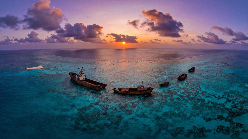 Aerial view of Second Thomas Shoal coral reef with rusting shipwreck on a sandbar beneath dramatic purple-orange sunset clouds, South China Sea maritime dispute — Philippines geopolitical risk 2026 assessment, CES Intelligence