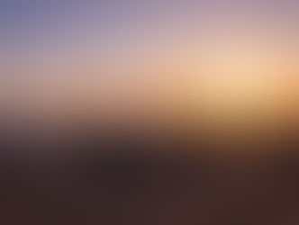 Aerial photograph of natural gas processing facility on Algerian Mediterranean coast at sunset, featuring three tall distillation towers emitting steam plumes, white spherical storage tanks in foreground, desert terrain, distant port cranes silhouetted against orange and purple sky