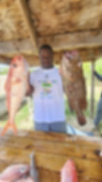 Man displaying a large red fish and a large brown fish