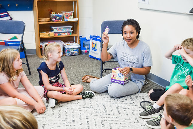Teacher and students sitting in a circle playing a learning game