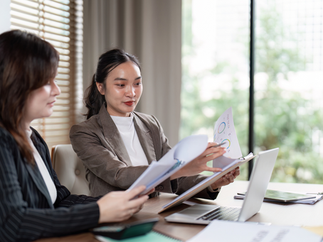 Twee zakelijk gekleedde vrouwen met papieren en een laptop
