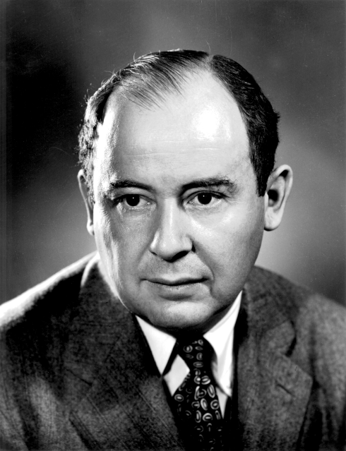 Man in suit and patterned tie, gazing seriously off-camera. Black and white portrait with a plain blurred background.