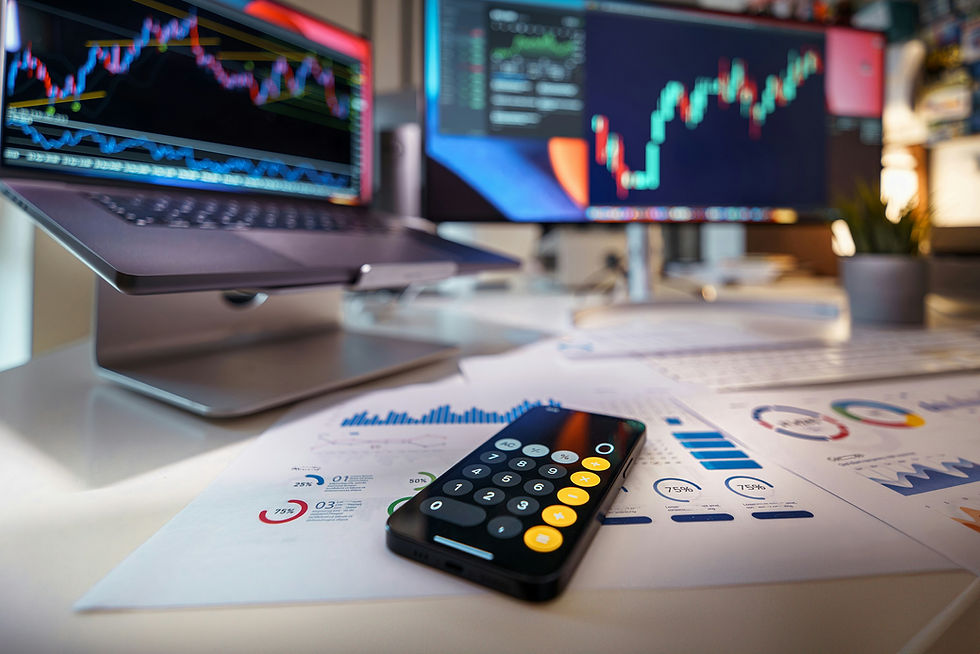 Calculator on a desk with stock market graphs