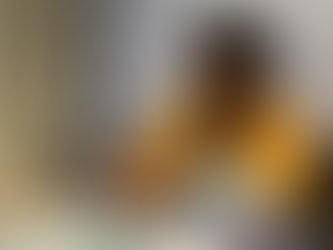 A woman in a yellow shirt sewing a quilt by hand