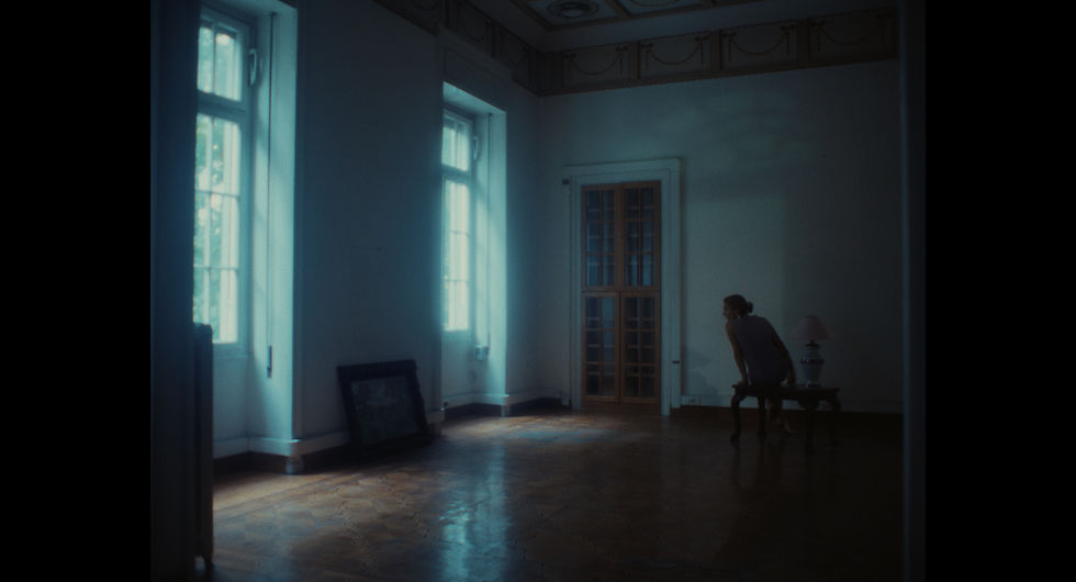 In this quiet frame, Iphigenia stands by the window, her gaze drifting between the world outside and the painting resting on the floor. It is unclear whether she is looking out towards freedom or reflecting on the art at her feet, capturing a moment of silent longing and ambiguity.