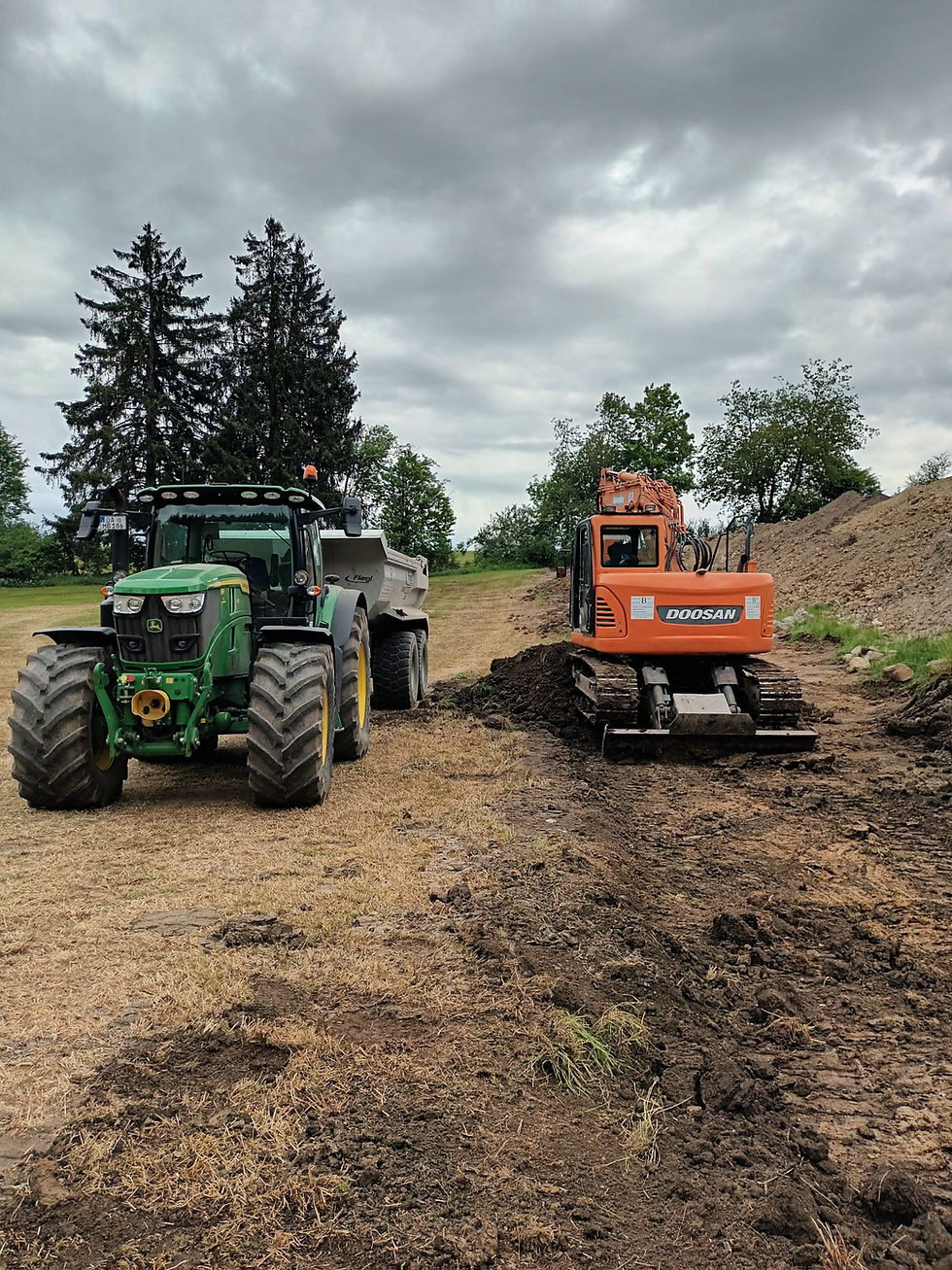 Ein grüner Traktor und ein oranger Bagger auf einem Feld.