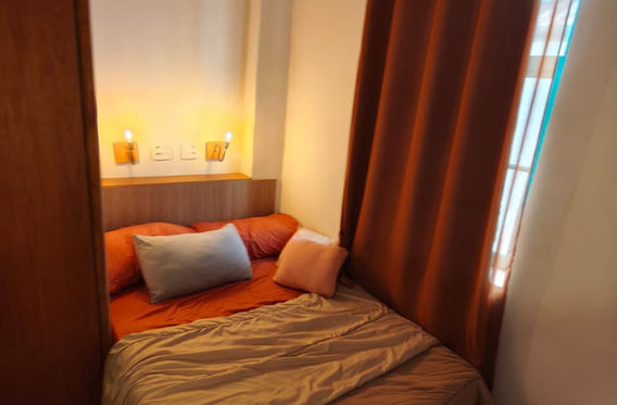 Cama com almofadas laranja ao lado de cortina