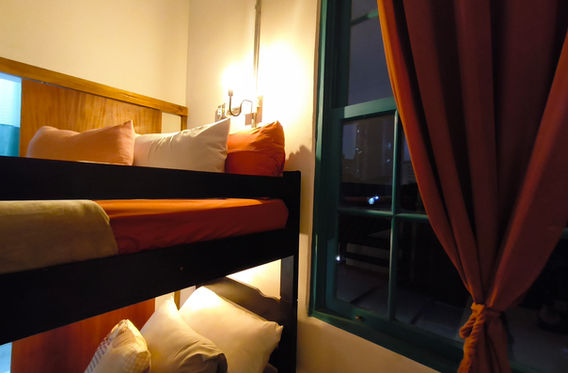 Beliche com luminárias de leitura e janela com cortina vermelha