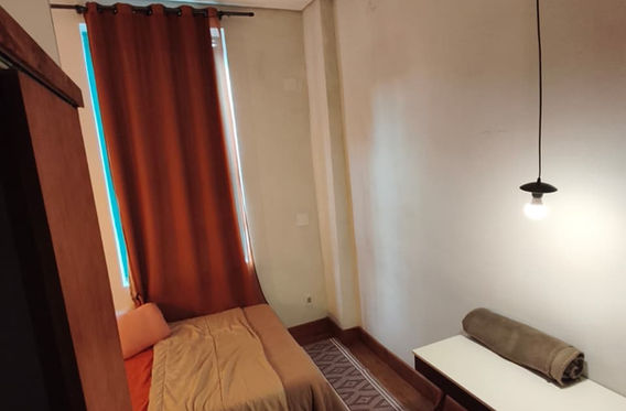 Cama sob luminária pendente com cortinas ao fundo