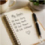 Open notebook with handwritten goals and a pen resting on the page.