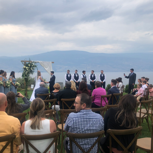 A beautiful moment as the bride and groom exchange vows against the scenic backdrop of a serene lake and rolling hills, surrounded by nature's breathtaking beauty.