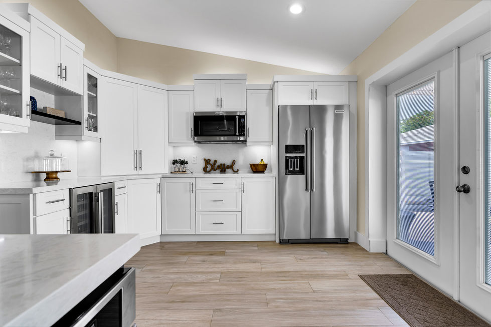 White kitchen with open-concept layout, custom pantry cabinet, recessed lighting, and wood plank floor tile in a Miami home