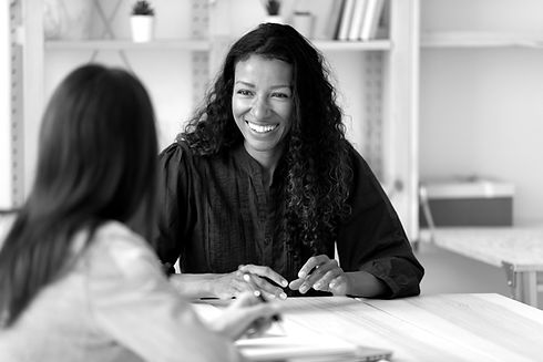 Smiling young African American woman talk with female colleagues brainstorm at office team