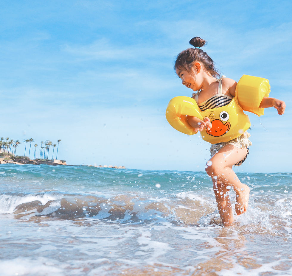 child with ducky arm floaties splashing in the waves