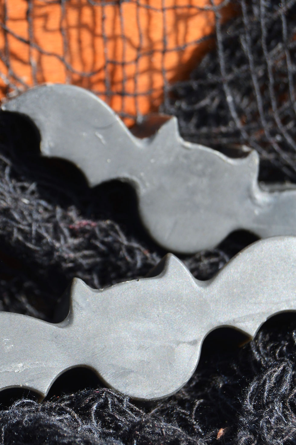 Close-up of three black bat soaps  against black mesh background